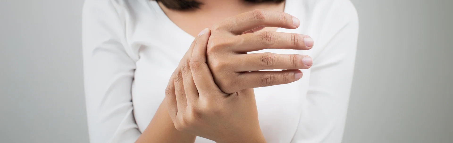 Egy nő a csuklóját fogja, miközben kézzsibbadást vagy kézfájdalmat tapasztal