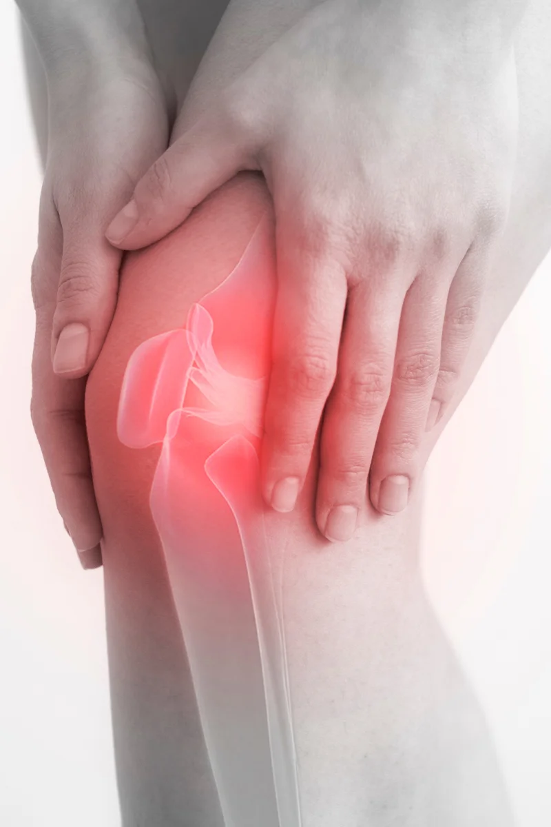 Térdfájdalom vizuális ábrázolása – kéz a térden, piros fájdalomjelzéssel